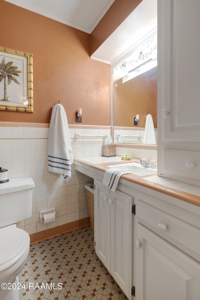 bathroom with vanity, tile patterned floors, crown molding, toilet, and tile walls