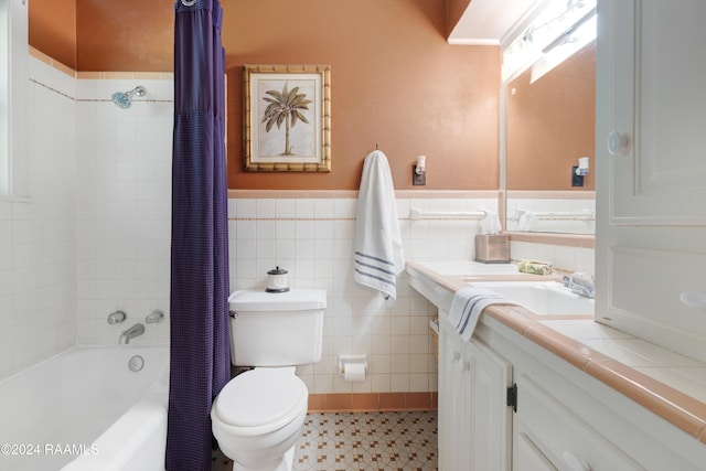 full bathroom with tile patterned floors, vanity, shower / bath combo with shower curtain, tile walls, and toilet