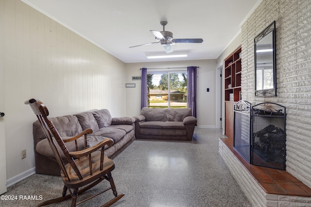 living room with a fireplace, wooden walls, ceiling fan, and crown molding