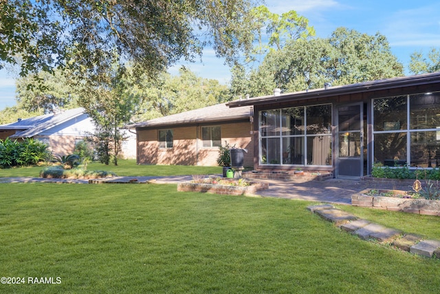 rear view of property featuring a lawn and a sunroom