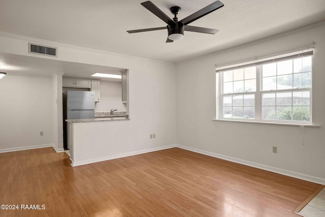 unfurnished living room with light hardwood / wood-style flooring, ceiling fan, and crown molding