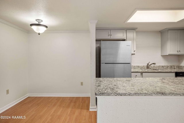 kitchen featuring stainless steel refrigerator, sink, crown molding, light hardwood / wood-style floors, and gray cabinets