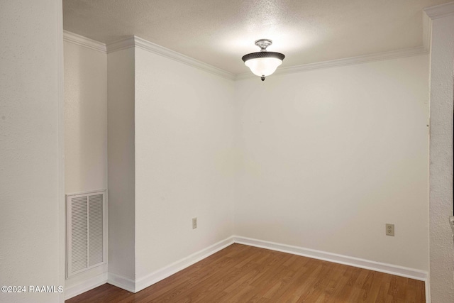 spare room with a textured ceiling, wood-type flooring, and crown molding