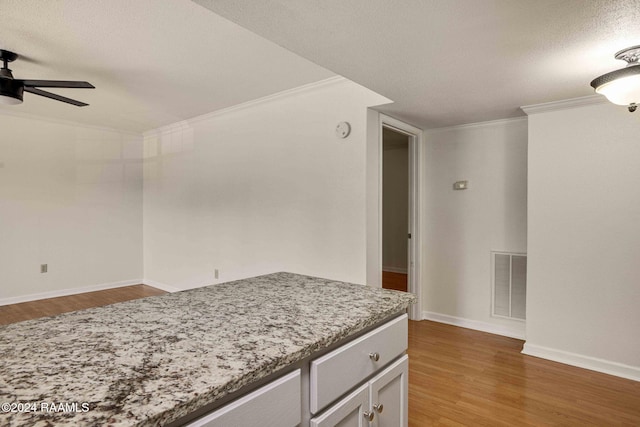 kitchen featuring ceiling fan, crown molding, wood-type flooring, and a textured ceiling