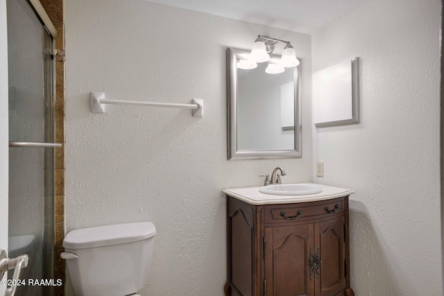 bathroom with an enclosed shower, vanity, and toilet