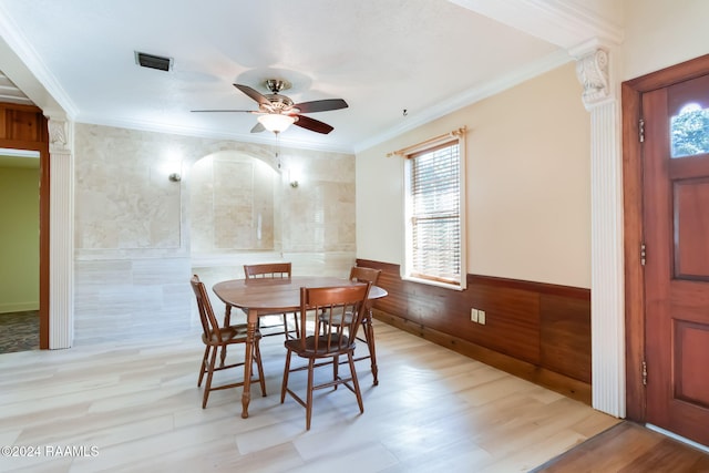 dining space with light wood-type flooring, ceiling fan, crown molding, and wood walls