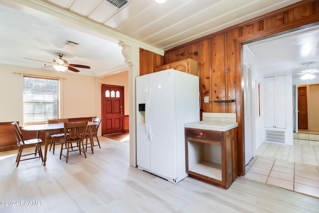 kitchen featuring light wood-type flooring, ceiling fan, wooden walls, crown molding, and white refrigerator with ice dispenser