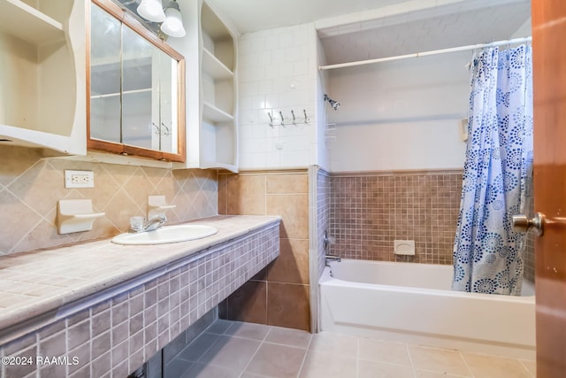 bathroom with tile walls, tile patterned floors, shower / bathtub combination with curtain, and sink