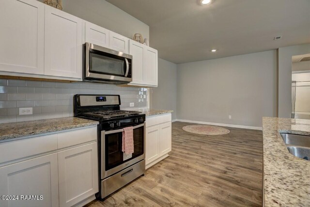 kitchen featuring stainless steel appliances, white cabinets, and light hardwood / wood-style flooring