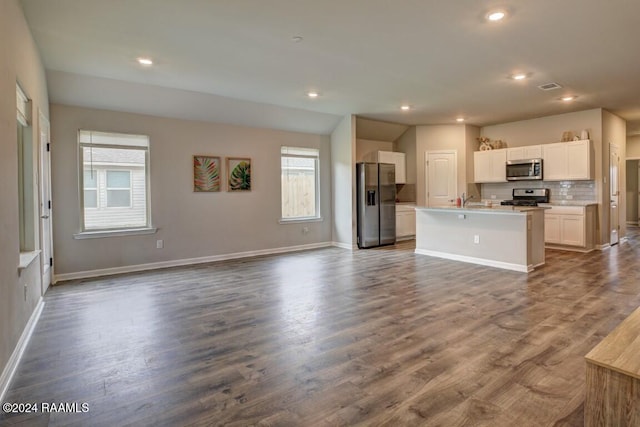 kitchen with a center island with sink, white cabinetry, appliances with stainless steel finishes, backsplash, and wood-type flooring