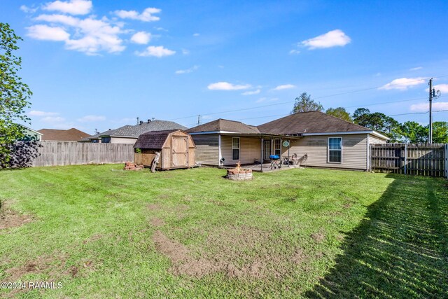 back of property featuring a patio, a shed, an outdoor fire pit, and a lawn