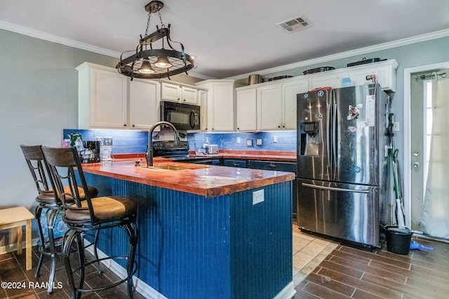 kitchen with white cabinetry, wood counters, pendant lighting, a breakfast bar area, and black appliances