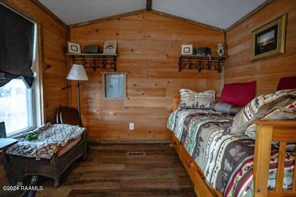 bedroom featuring wooden walls, lofted ceiling, and hardwood / wood-style floors