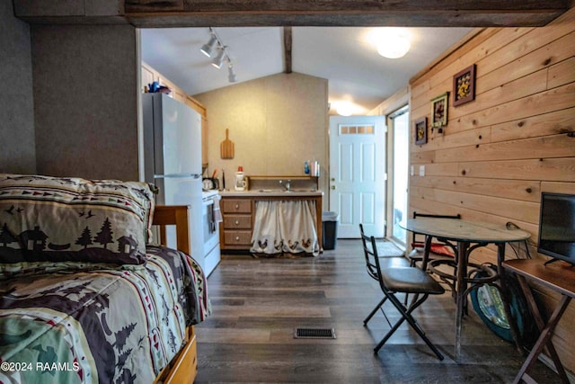 bedroom featuring dark hardwood / wood-style flooring, vaulted ceiling, white refrigerator, wooden walls, and rail lighting