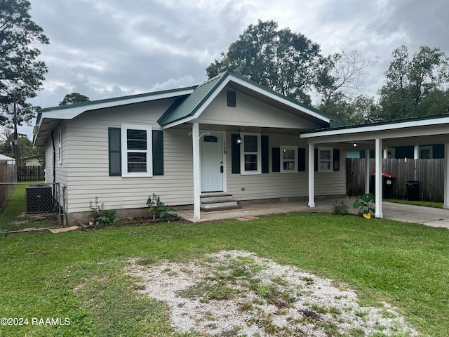 view of front of home with metal roof, a carport, a front lawn, and fence