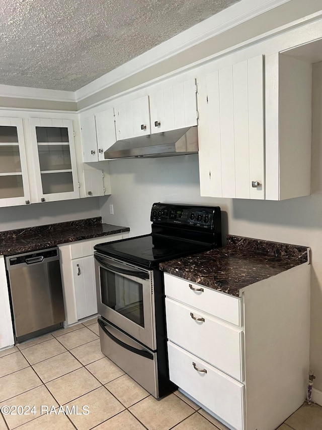 kitchen with light tile patterned flooring, appliances with stainless steel finishes, dark stone countertops, a textured ceiling, and white cabinets