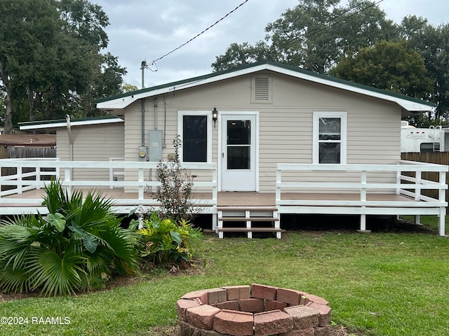 back of house with a fire pit, a yard, and a deck