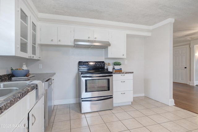 kitchen featuring dark countertops, under cabinet range hood, light tile patterned floors, white cabinets, and stainless steel appliances