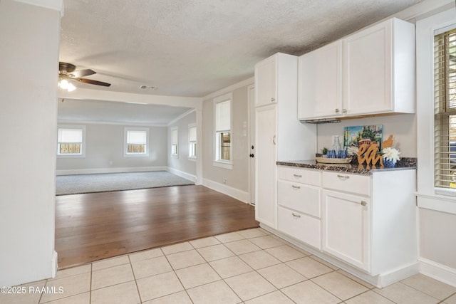 kitchen featuring light tile patterned floors, a textured ceiling, open floor plan, and white cabinetry