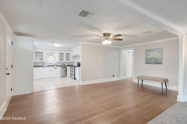 living room with ornamental molding, light wood-style floors, visible vents, and a textured ceiling