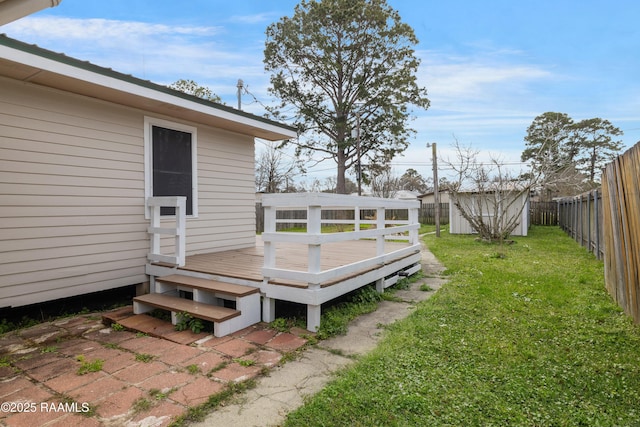 wooden terrace with an outdoor structure, a yard, a fenced backyard, and a storage unit