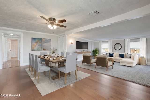 dining room with visible vents, attic access, ornamental molding, wood finished floors, and a textured ceiling