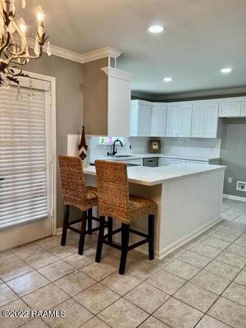 kitchen with kitchen peninsula, crown molding, a breakfast bar, and white cabinets