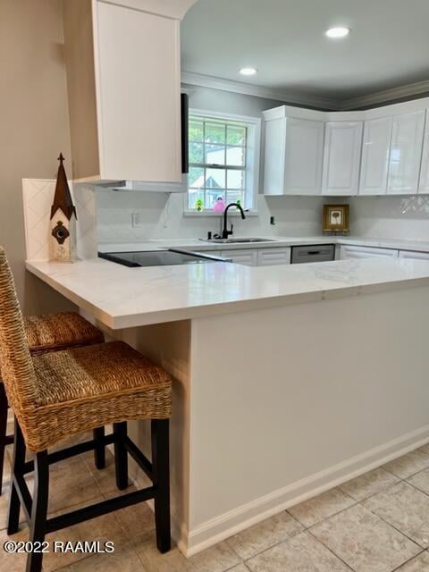 kitchen with kitchen peninsula, sink, a breakfast bar, and white cabinets