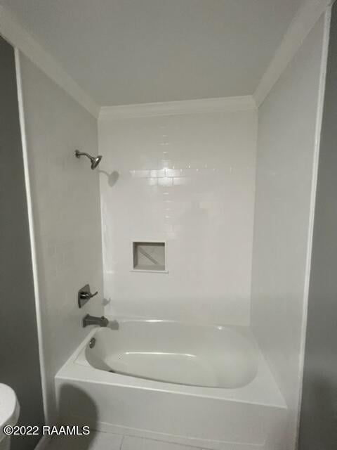 bathroom featuring bathing tub / shower combination, tile patterned floors, toilet, and ornamental molding