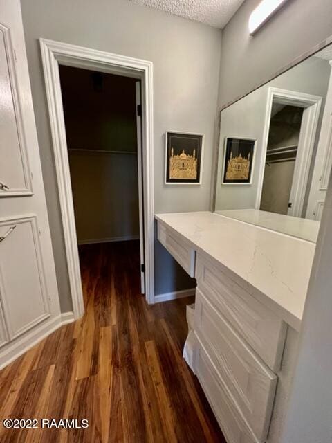 corridor with a textured ceiling and dark hardwood / wood-style flooring