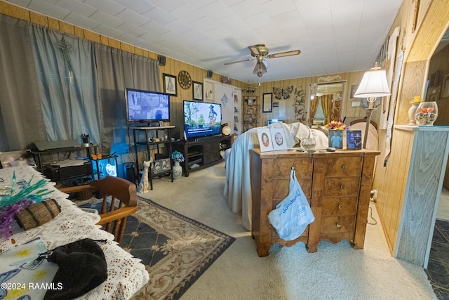 carpeted living room featuring ceiling fan and wood walls