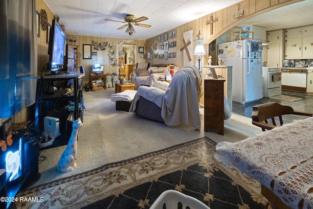 carpeted living room featuring ceiling fan and wooden walls