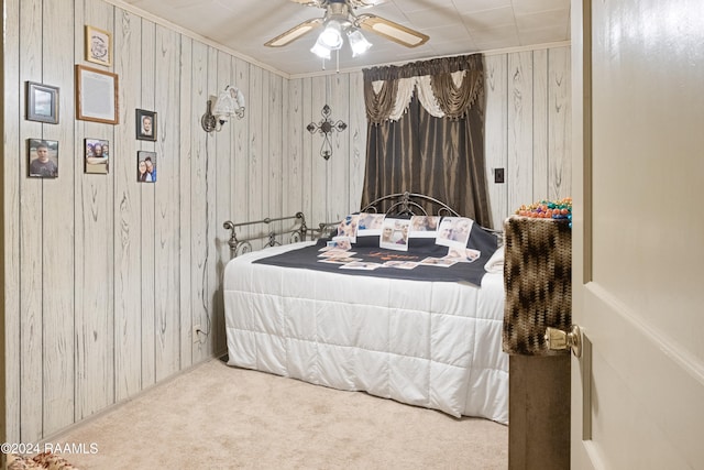 carpeted bedroom featuring ceiling fan and wood walls