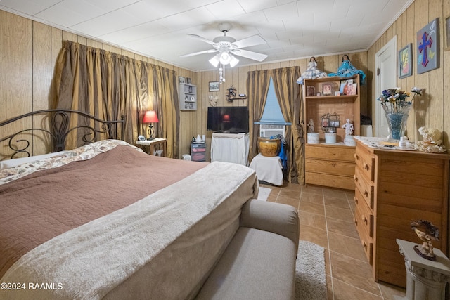 bedroom with ceiling fan, wooden walls, and light tile patterned floors