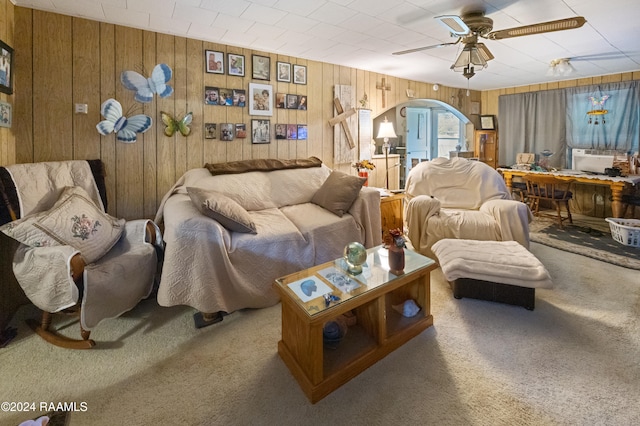 living room featuring carpet, ceiling fan, and wood walls