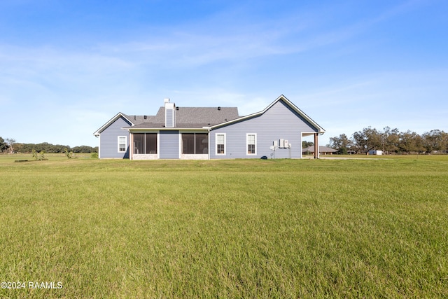 rear view of house featuring a yard and a sunroom