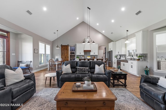 living room featuring hardwood / wood-style flooring, a barn door, sink, and high vaulted ceiling