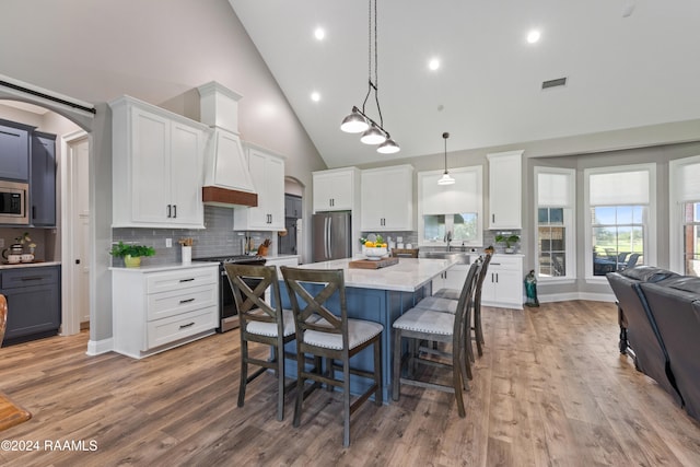 kitchen featuring white cabinets, stainless steel appliances, high vaulted ceiling, and a kitchen island