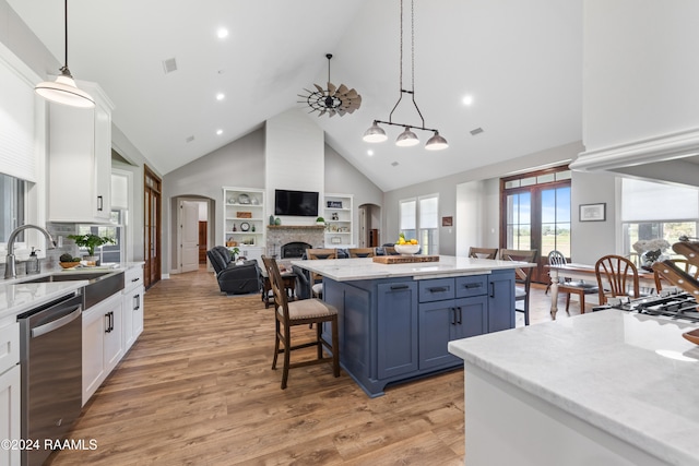 kitchen with stainless steel dishwasher, decorative light fixtures, white cabinets, and sink