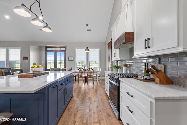 kitchen with gas stove, blue cabinets, pendant lighting, light hardwood / wood-style floors, and white cabinetry