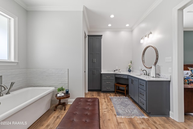 bathroom with hardwood / wood-style floors, vanity, a tub to relax in, and ornamental molding