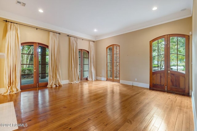 foyer entrance featuring light hardwood / wood-style floors, french doors, a healthy amount of sunlight, and crown molding