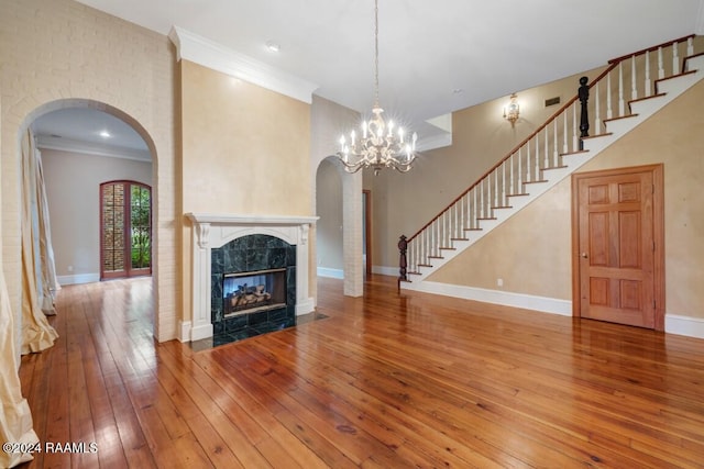 unfurnished living room featuring a fireplace, wood-type flooring, a chandelier, and ornamental molding