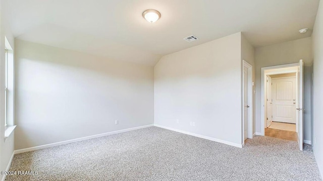 unfurnished room featuring lofted ceiling and light carpet