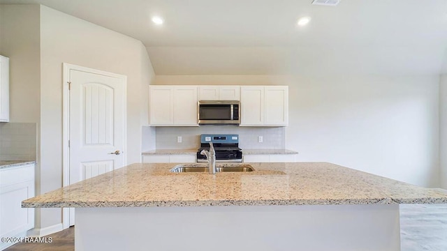 kitchen featuring decorative backsplash, a kitchen island with sink, white cabinets, and stainless steel appliances