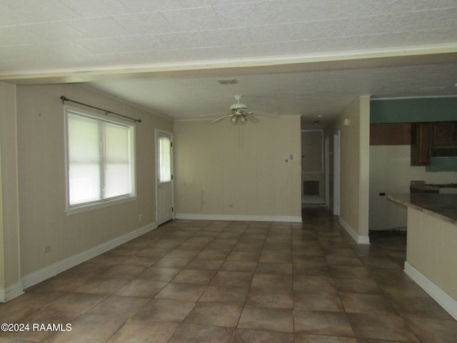 unfurnished living room with dark tile patterned flooring and ceiling fan