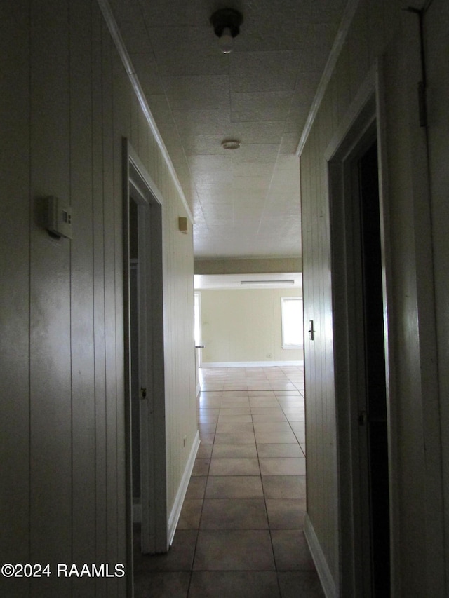 hallway with tile patterned flooring and wood walls