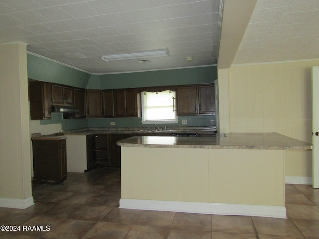 kitchen with dark brown cabinetry, tile patterned flooring, a kitchen island, crown molding, and decorative backsplash