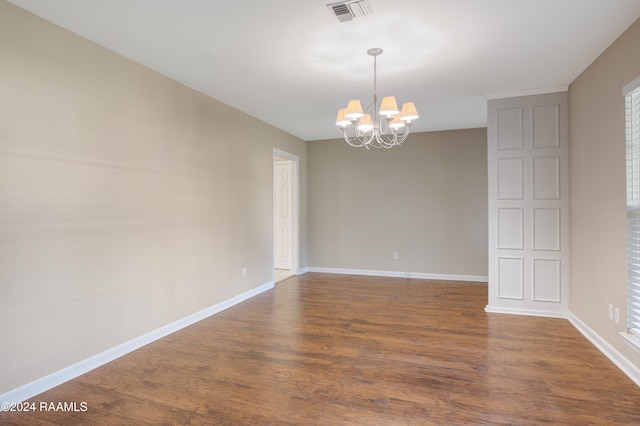 unfurnished room with dark wood-type flooring and a chandelier