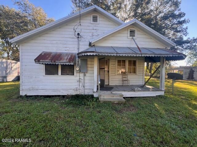 rear view of property featuring a yard and a porch